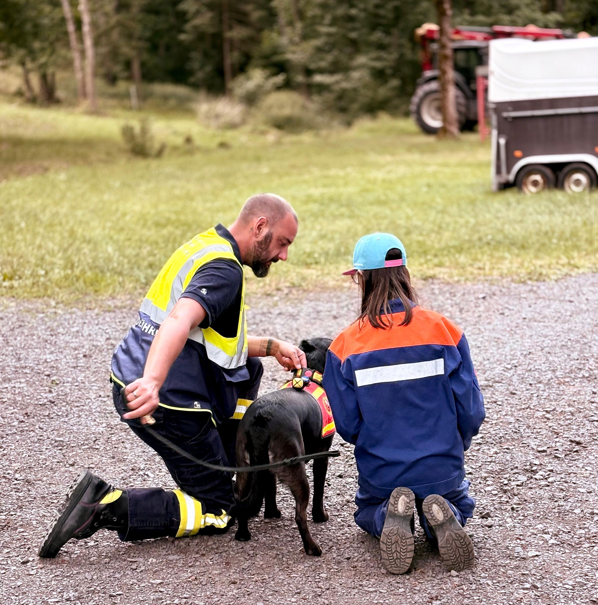 Hundeführer spricht mit Jugendfeuerwehr Mädchen und hält einen Hund an der Leine